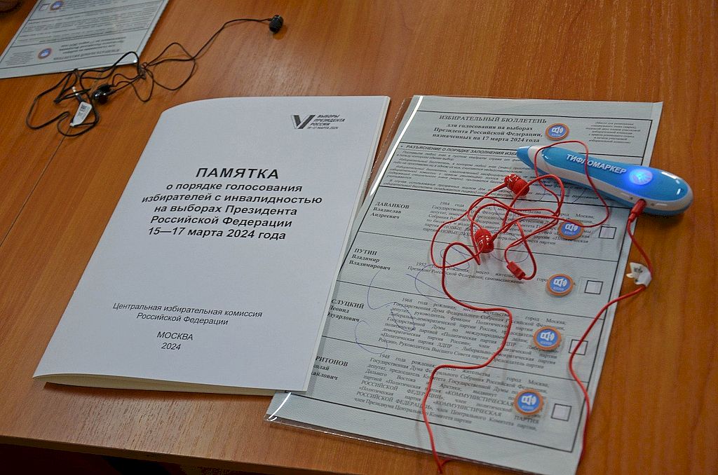 На фотографии изображена памятка о порядке голосования избирателей с инвалидностью на выборах Президента РФ, бюллетень и тифломаркер с наушниками