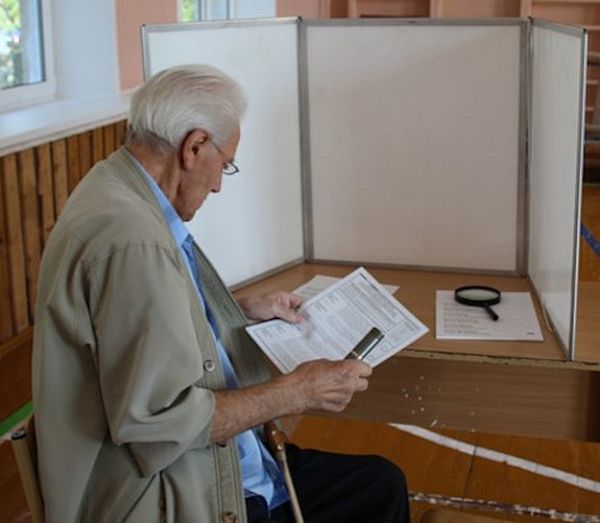 Избиратель в кабне для голосования, оборудованной увеличительными приборами