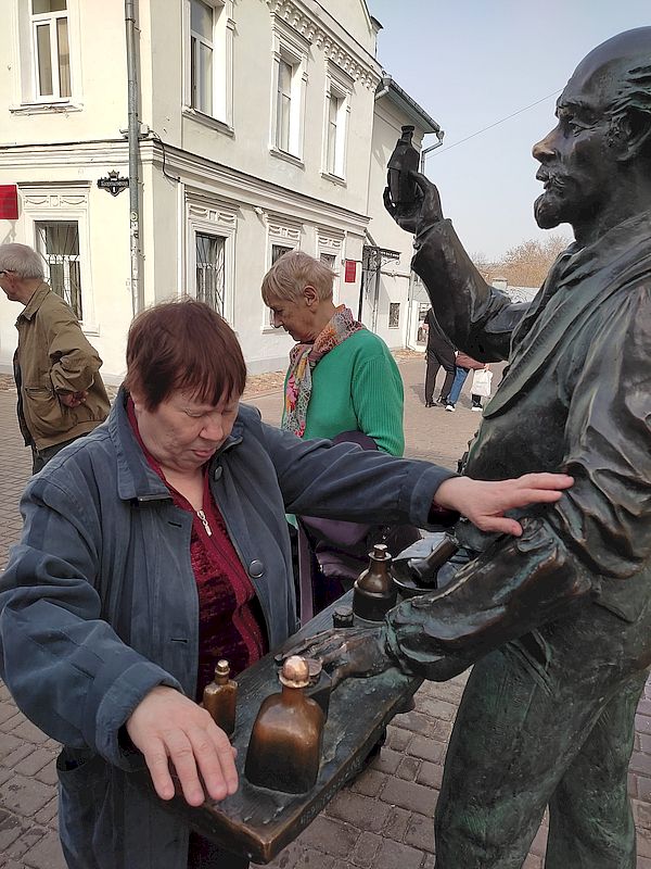 Женщина тактильно осматривает скульптуру "Аптекарь"