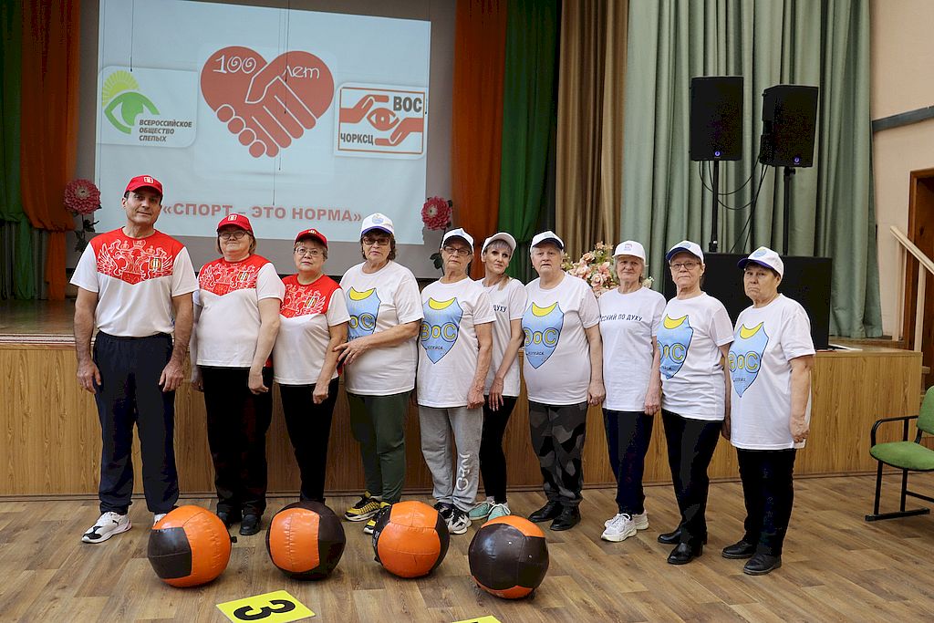 учвстники мероприятия стоят в линию. перед ними лежат большие оранжевые мячи