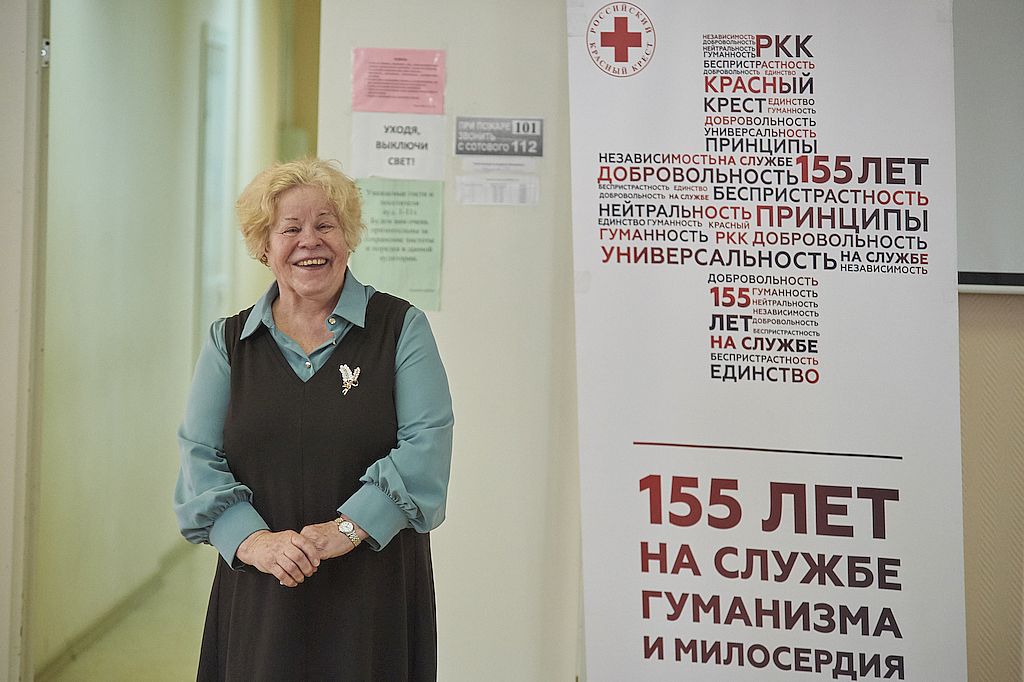 Председатель Красноярской РО ВОС Валентина Ивановна Прудкова стоит около баннера организации "Красный крест"