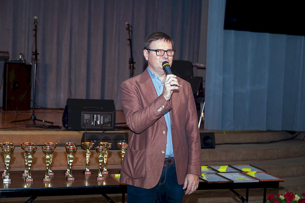 церемония награждения. Заместитель генерального директора КСРК ВОС Антон Федотов говорит в микрофон. За ним на столе стоят кубки и лежат медали