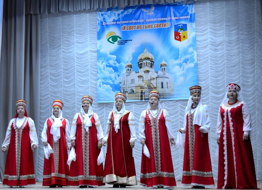 семь женщин в красных русских народных костюмах и головных уборах исполняют песню