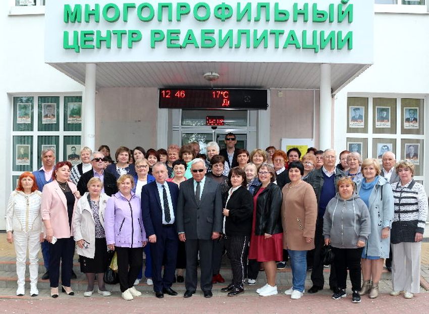 Групповое фото участников семинара на крыльце Многопрофильного центра реабилитации. По бокам на заднем плане на стенах - фотографии ветеранов ВОВ.