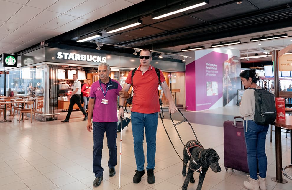 сотрудник аэропорта сопровождает незрячего с собакой проводником