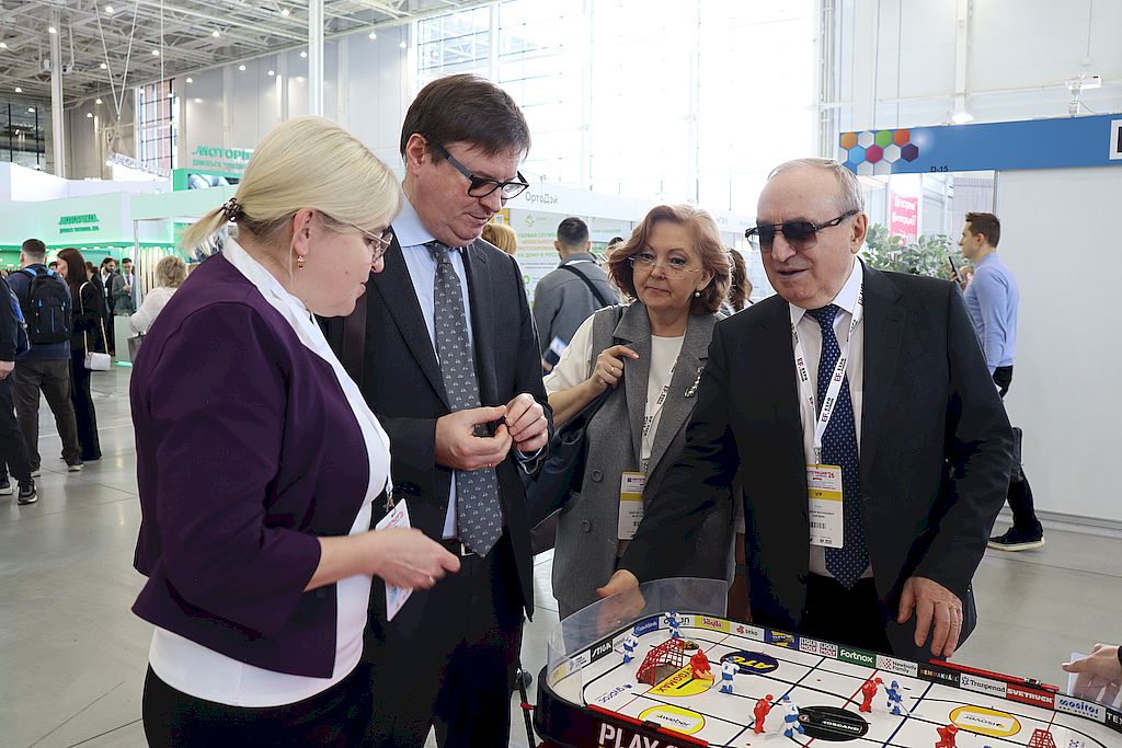 Антон Федотов демонстрирует Владимиру Сипкину и Марие Востриковой настольный хоккей