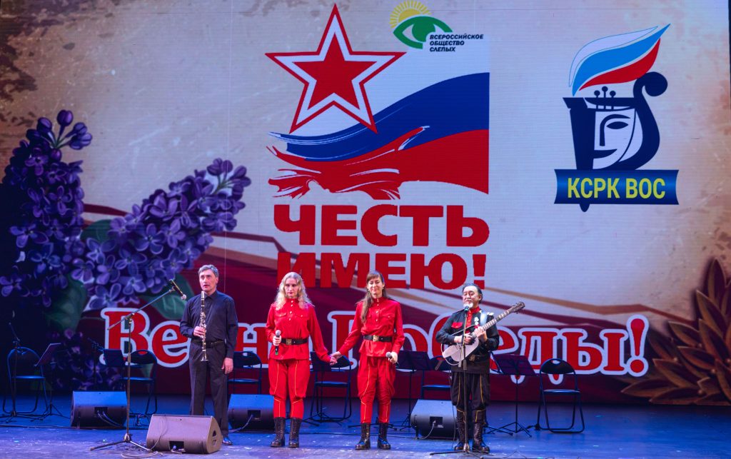 На сцене выступают артисты, из них - две женщины в красной форме