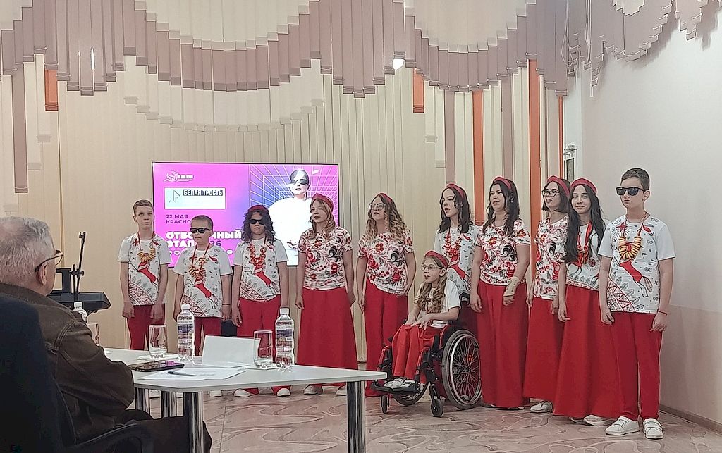 на фотографии ансамбль из 11 детей. Они одеты в цветные футболки и красный низ