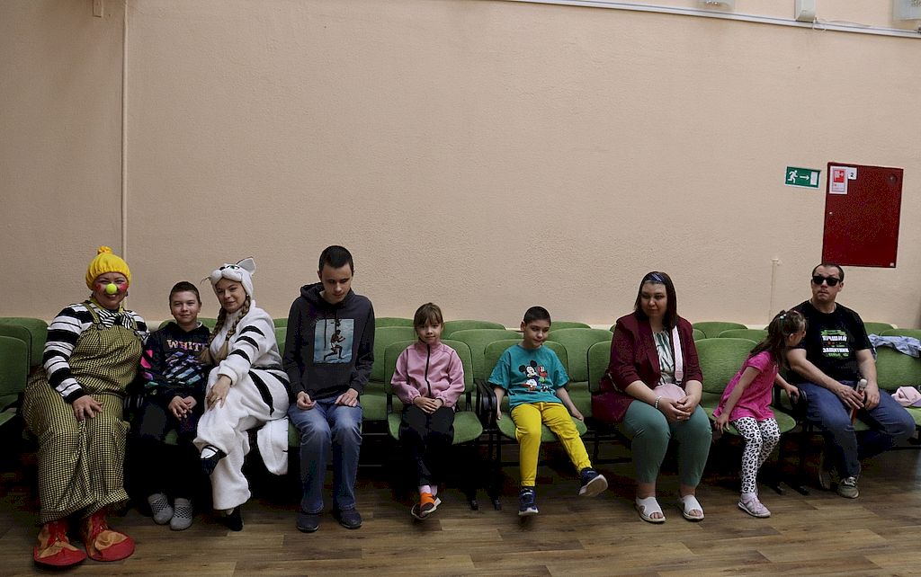 дети и их родители сидят на диване перед началом мероприятия