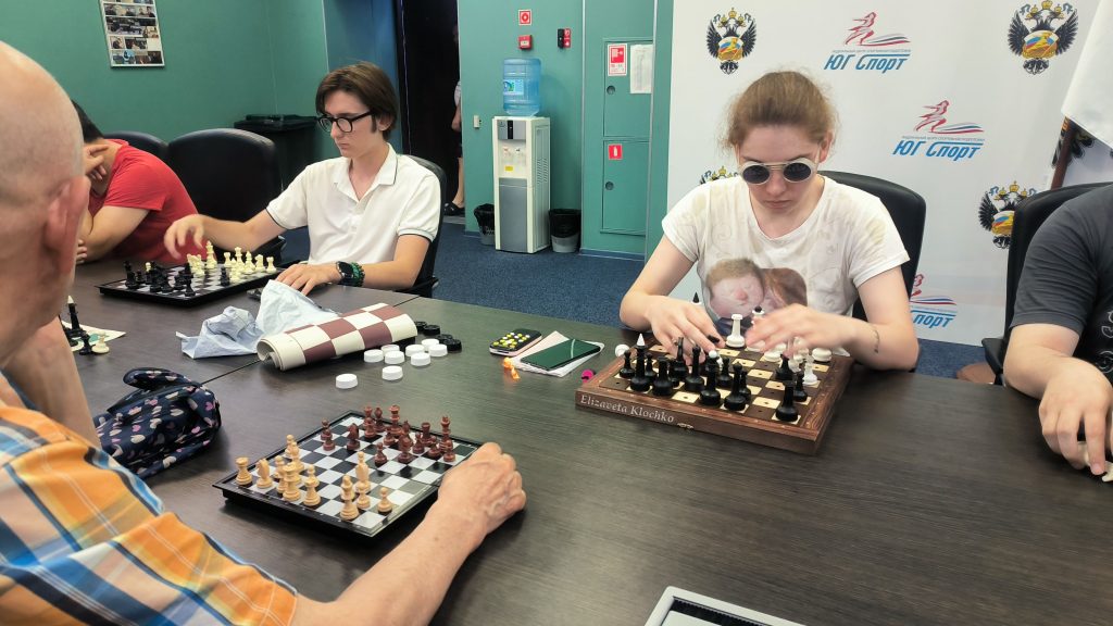 Девушка в очках расставляет фигуры на шахматной доске