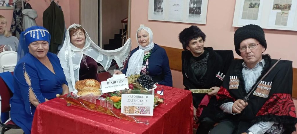 Участники в национальных костюмах сидят за столом