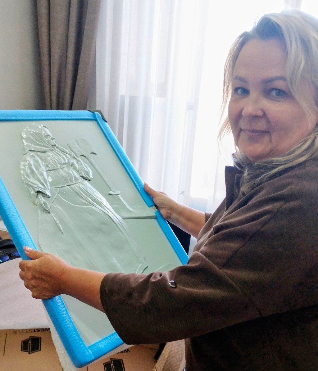 Женщина держит в руках тактильную картину