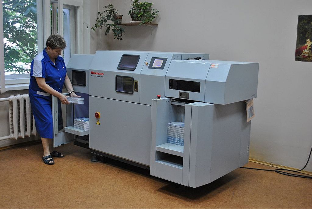 сотрудник работает за станком в типографии