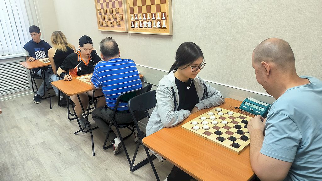 Участники соревнований сидят за игровыми досками