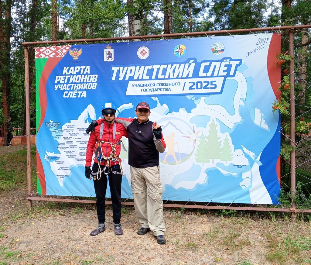 Тренер и спортсмен стоят на фоне баннера 